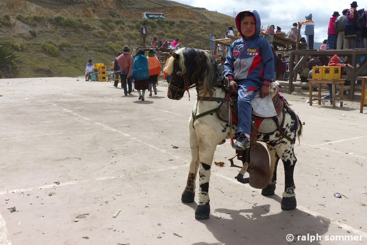 Junge auf Pferdeattrappe beim Rodeo in Zumbahua, Ecuador